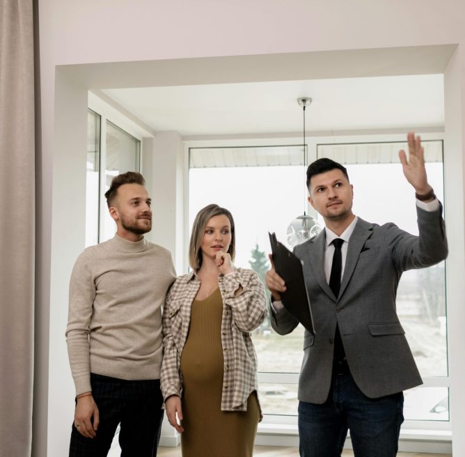 A pregnant woman and her partner explore a new house with a real estate agent.